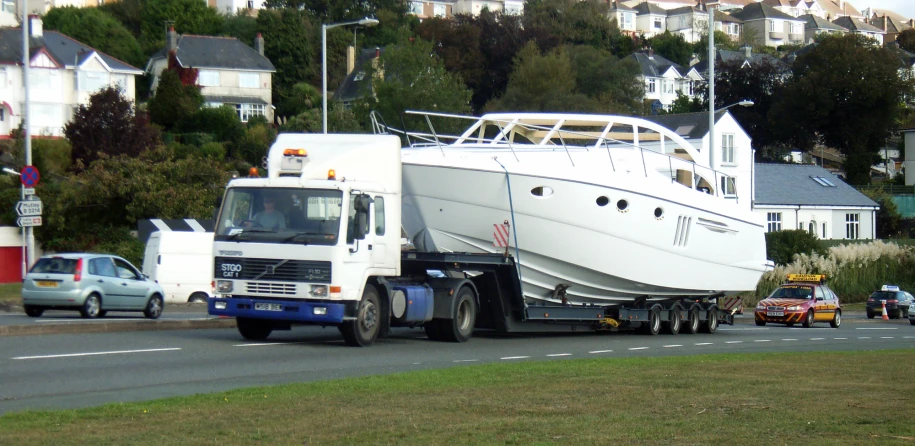 a large white truck parked next to a white boat