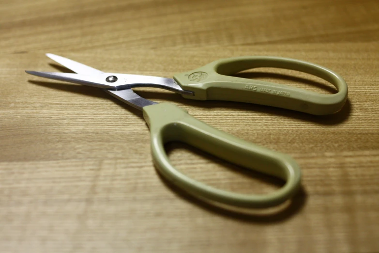 the pair of scissors is on the wooden table