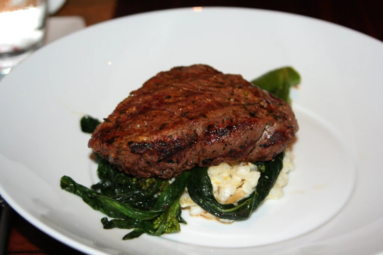 a plate of food with meat and greens on top