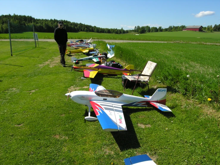 many airplanes sitting on the grass with a man standing near them