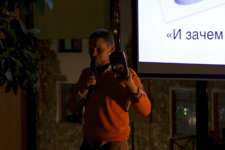 man is standing in front of a projection screen talking on his cell phone