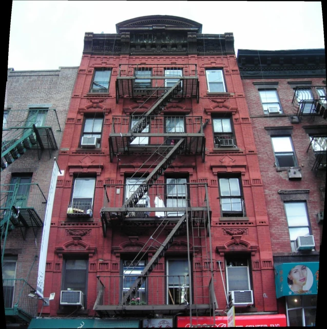 a tall red brick apartment building with stairs leading to it