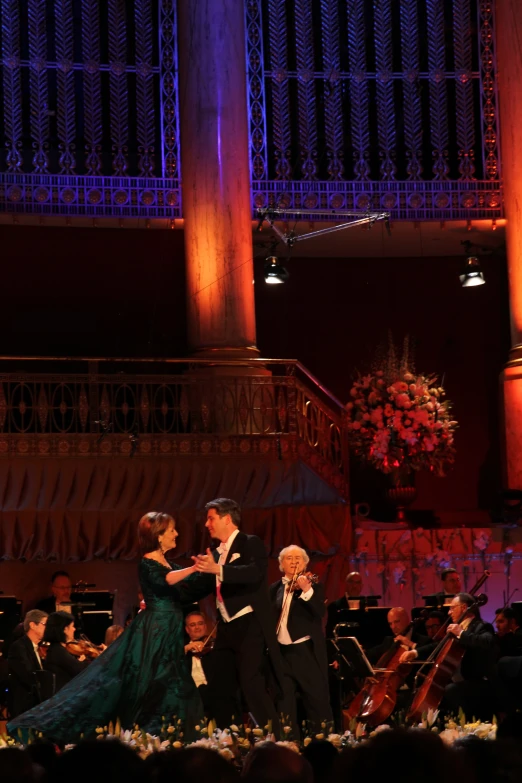 a couple performing on stage with orchestra