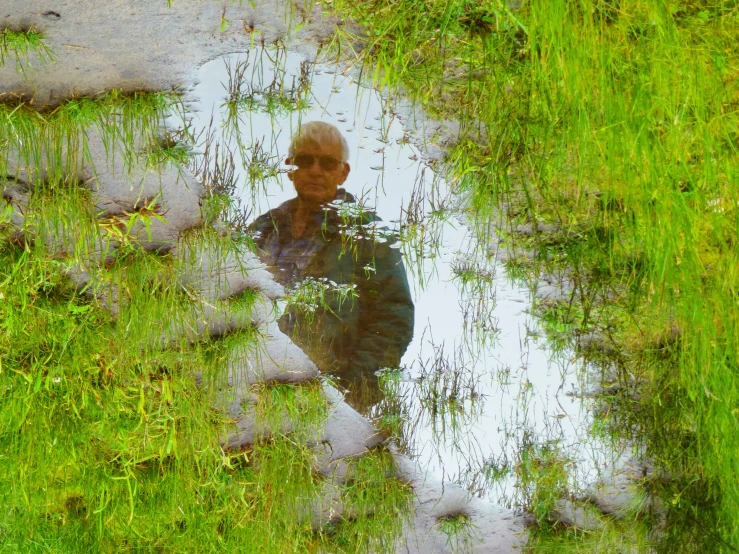 a man sitting on the grass near a pond