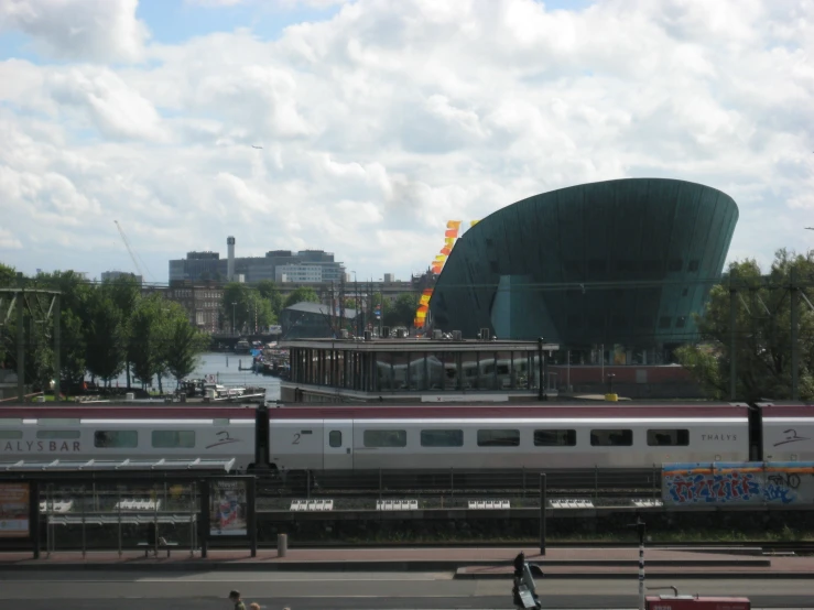 people walk along the street, past a train station