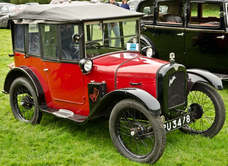 old time fashioned red and black motor car on grass