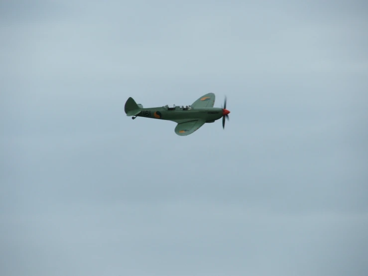 a green airplane in flight with a sky background