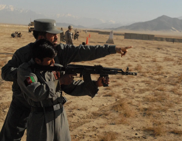 a man pointing at soing while another man holds a gun