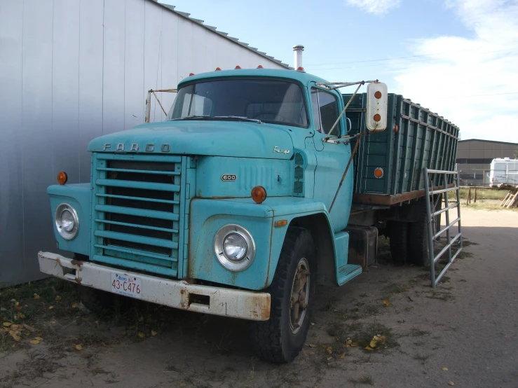 a large green truck parked next to a barn