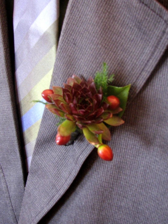small flower pinned on lapel of man wearing grey jacket