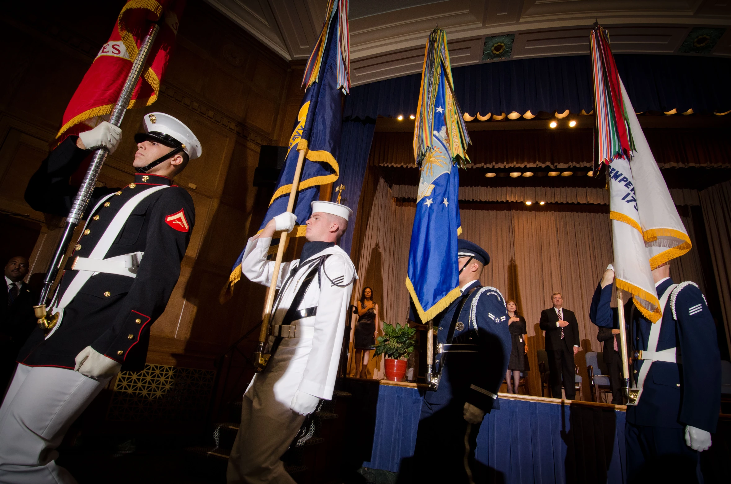 three people in military uniforms standing near flags