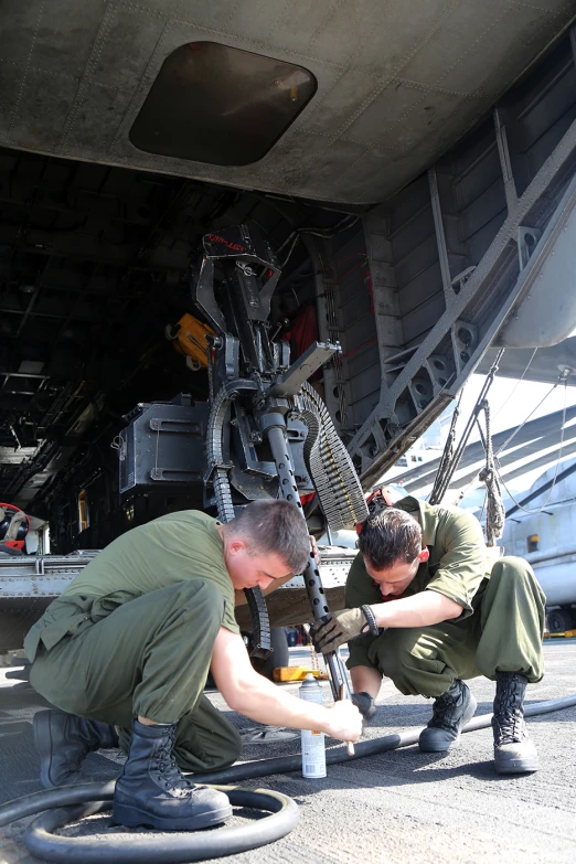 two men are inspecting soing in the back of a airplane