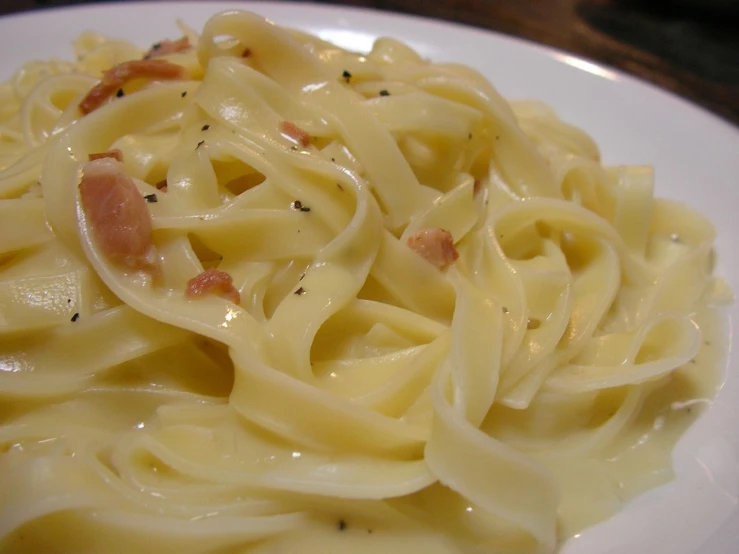 a plate full of pasta with sauce, bacon and sprinkles