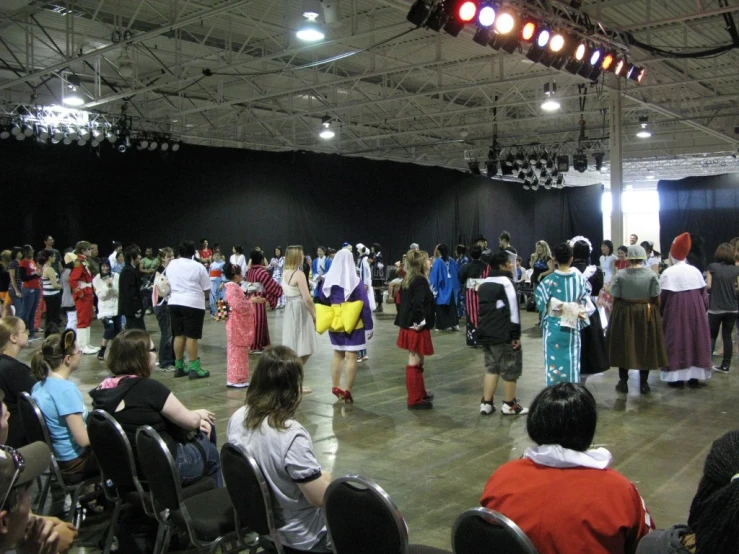 large crowd of people in chairs with one group on stage