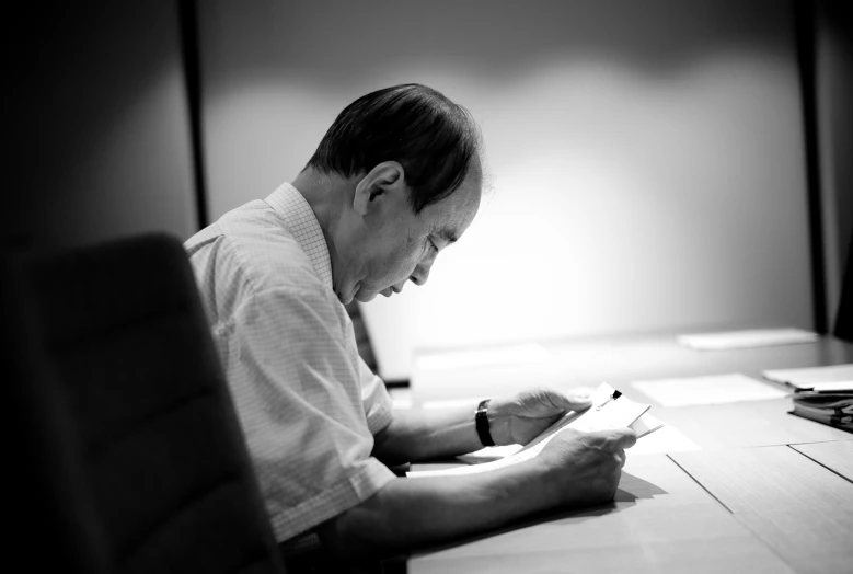 a man sits at a desk writing in a book