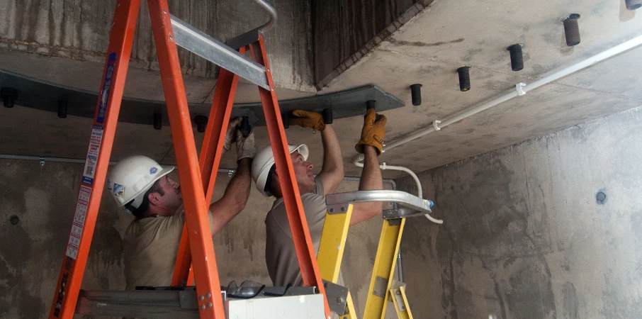 a man with a helmet and safety gear working on a ceiling