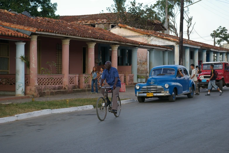 people riding bikes and cars down a street