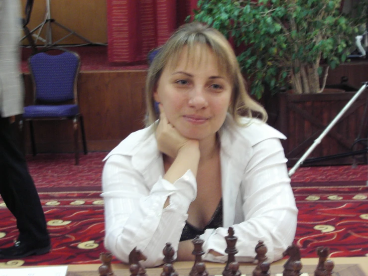 a beautiful woman sitting at a table with a chess board