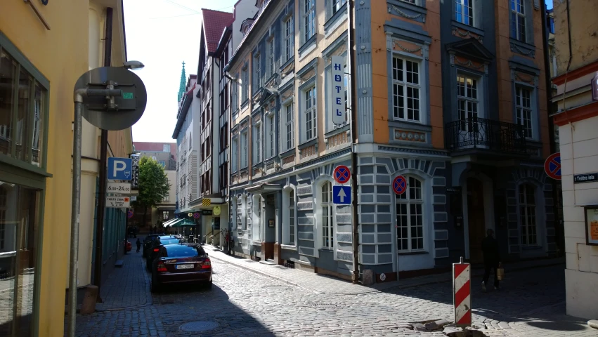 people are walking down a narrow street past a very large building