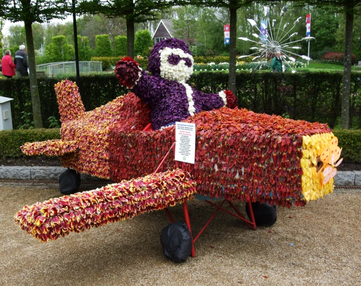 a teddy bear is sitting on the side of an airplane made out of yarn