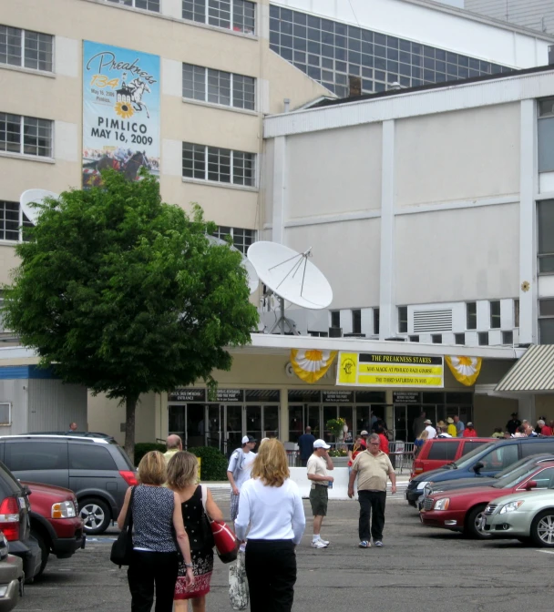 several people walking on a walkway next to parked cars