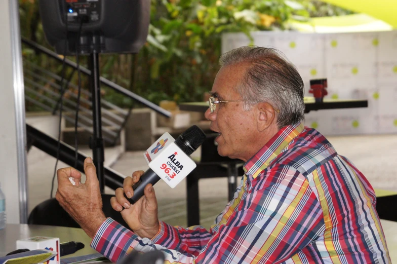 a man sitting in front of a microphone holding a radio