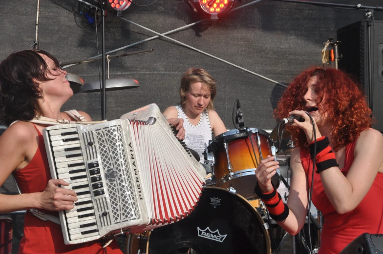 three women with red hair and red head dresses playing the accordion