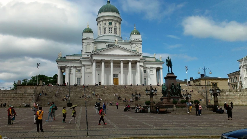 many people are walking around outside a large white building