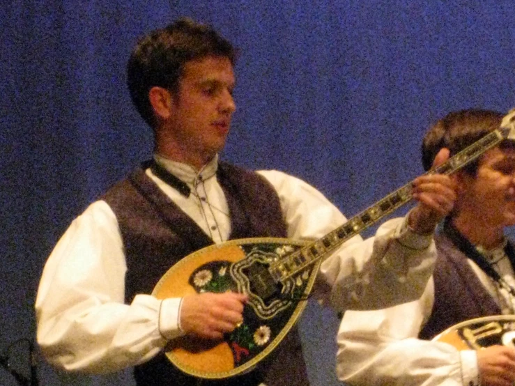 a man holding a musical instrument next to another man