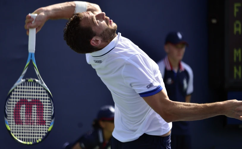 a man with a beard serving a tennis ball