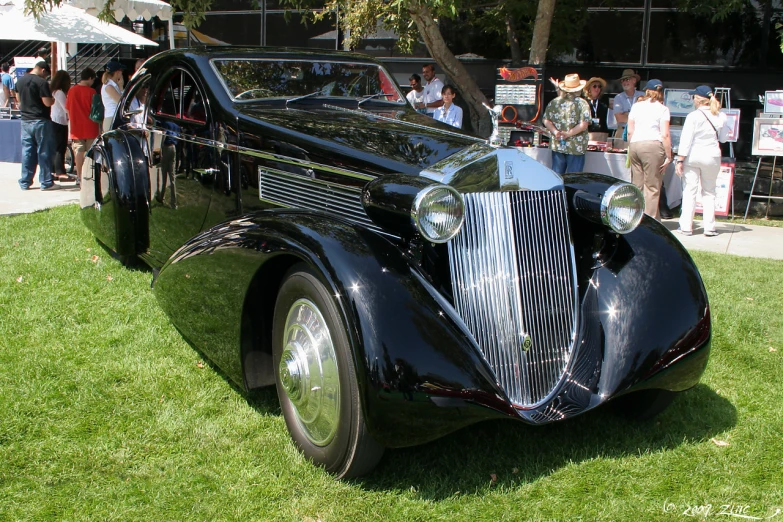 an old fashioned car sitting on top of green grass