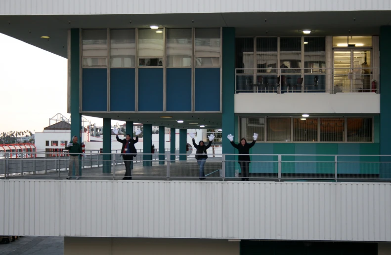 some people stand on a balcony in front of the building