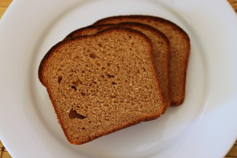 three pieces of brown bread sit on a white plate