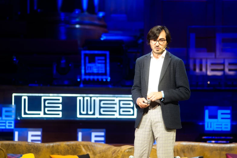 a man is standing on a stage wearing glasses