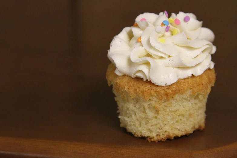 a cupcake is on the table with icing and sprinkles