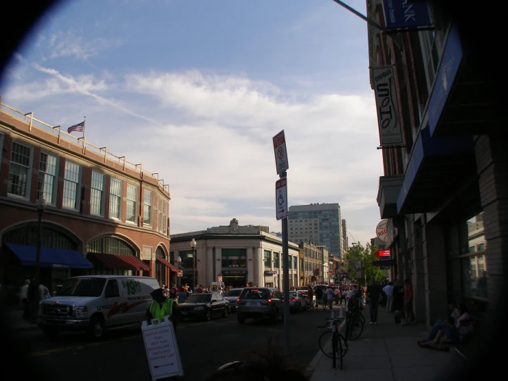 several cars are stopped at a red light while a bicyclist sits on the sidewalk