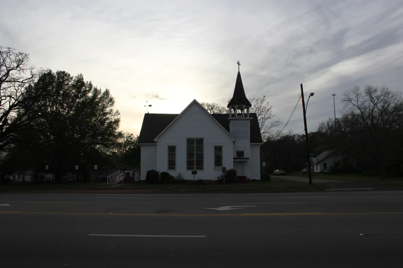 an old white house sitting on the side of a road