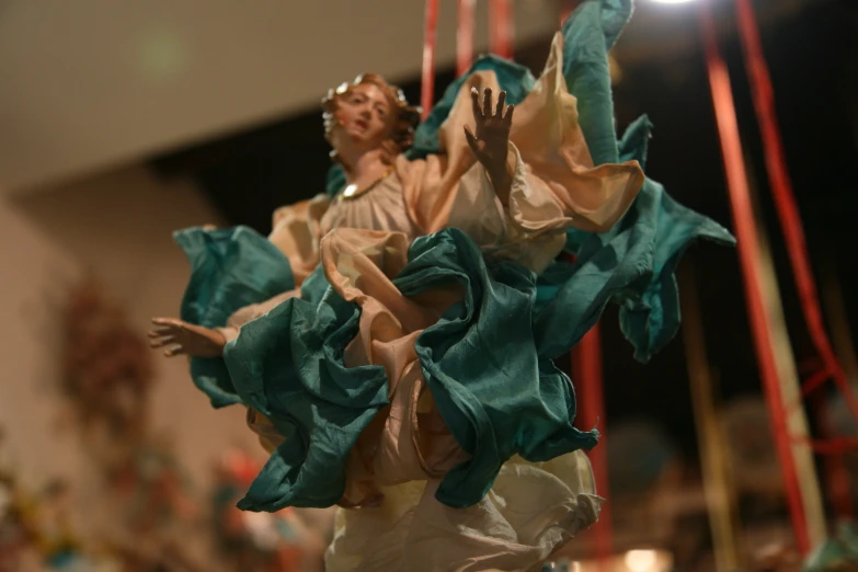 some green cloths hang from the top of a figurine