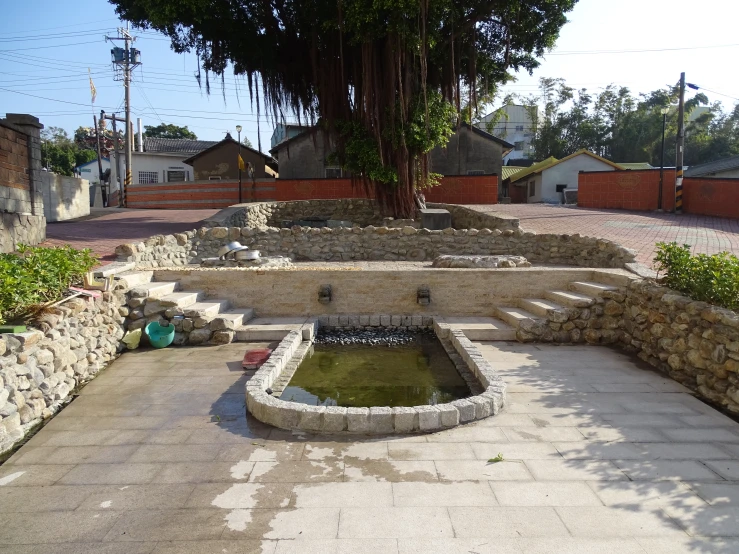 a stone pathway next to a tree that's above a water feature