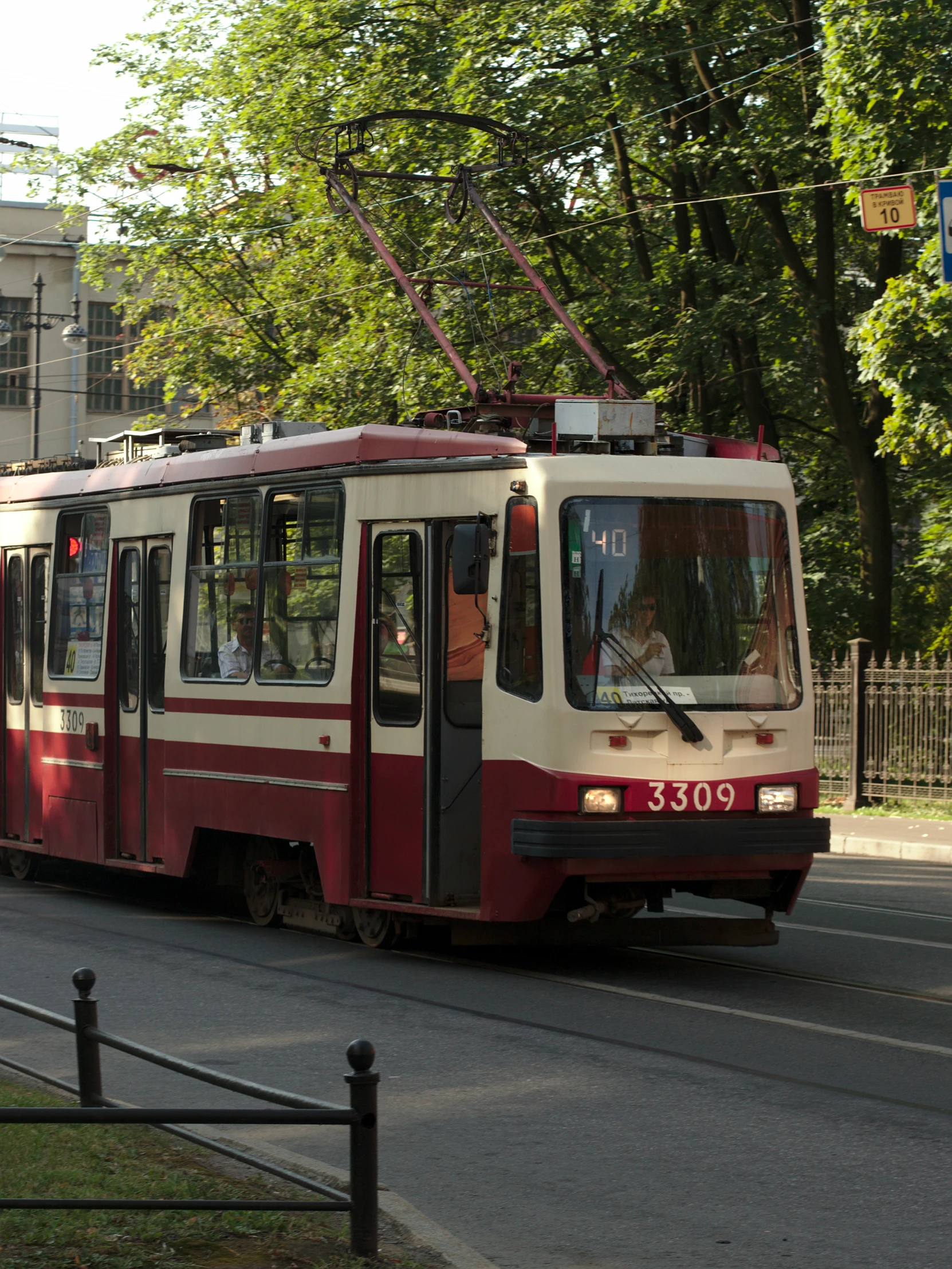 a red and white trolley on the road, with people walking in it