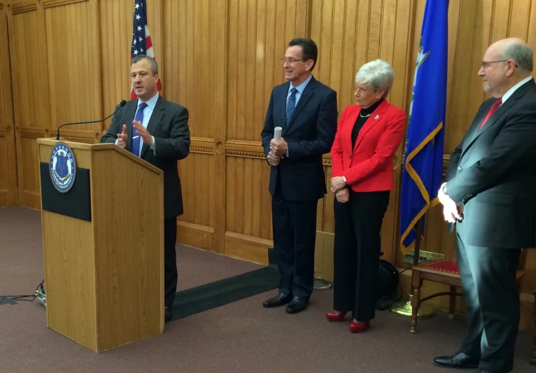 three men are standing at podiums in a room