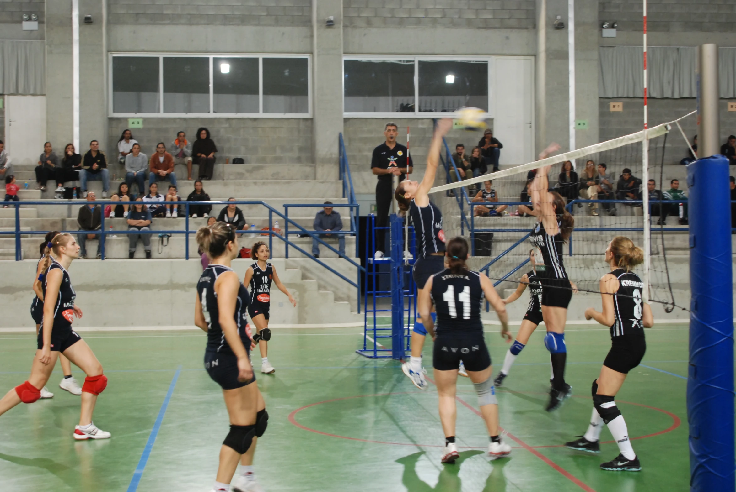 women in black uniforms playing volleyball against a crowd