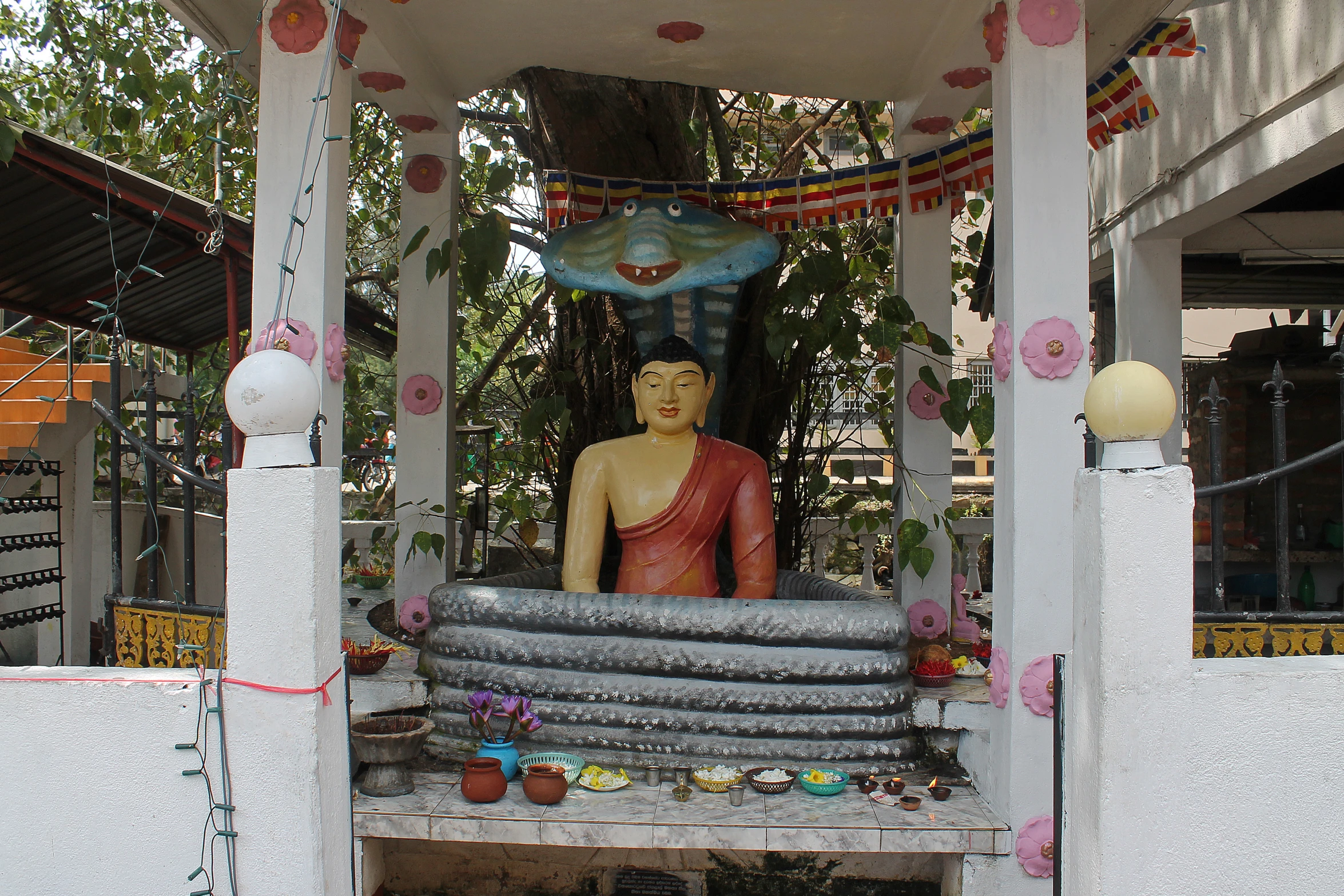 a buddha statue sitting on a bed in front of a tree