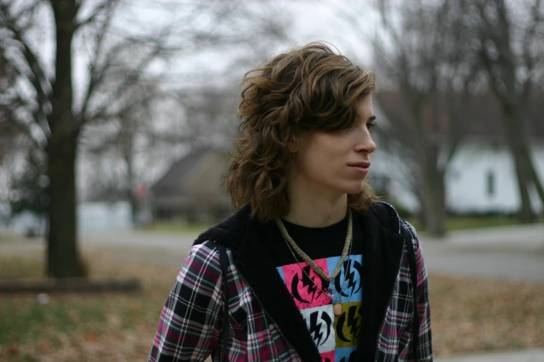 a young man standing in front of some trees