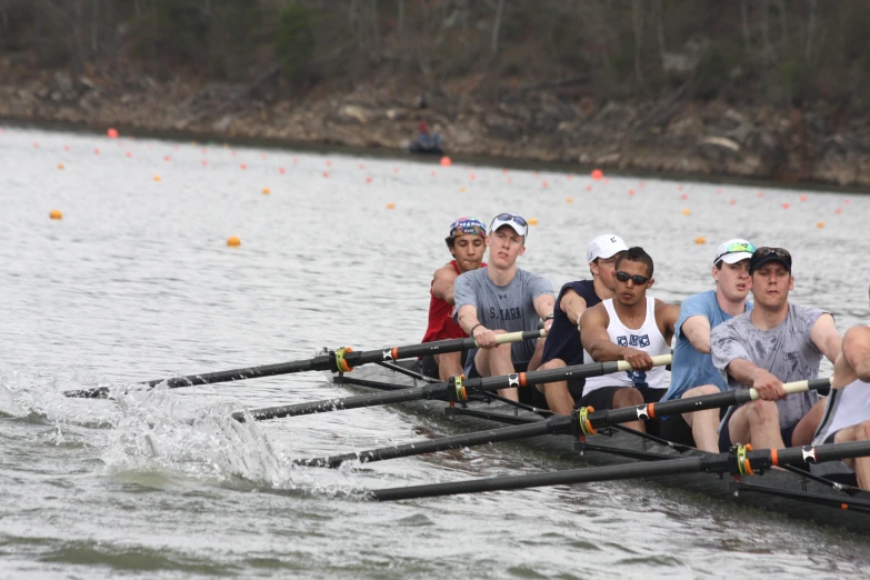 four men and one woman row in a boat