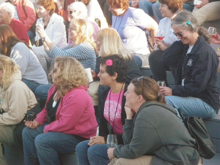 a large group of people sitting next to each other on bench