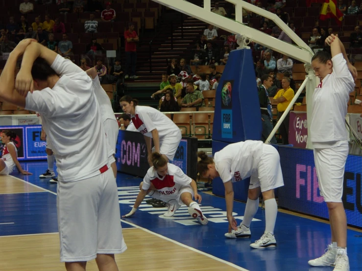 players in white uniforms on a blue and wood court