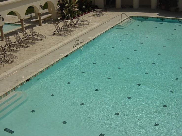 a large swimming pool is empty by some patio furniture