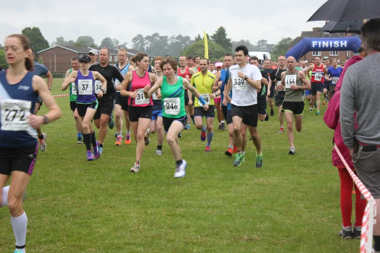 a group of people running down a grass covered field