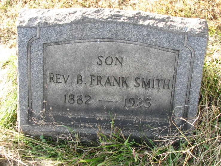 a tombstone in the grass has a name on it